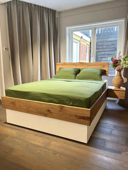 eikenhouten massief bed met witte lades eronder en een groen Egyptisch katoen dekbedovertrek