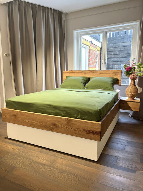 eikenhouten massief bed met witte lades eronder en een groen Egyptisch katoen dekbedovertrek